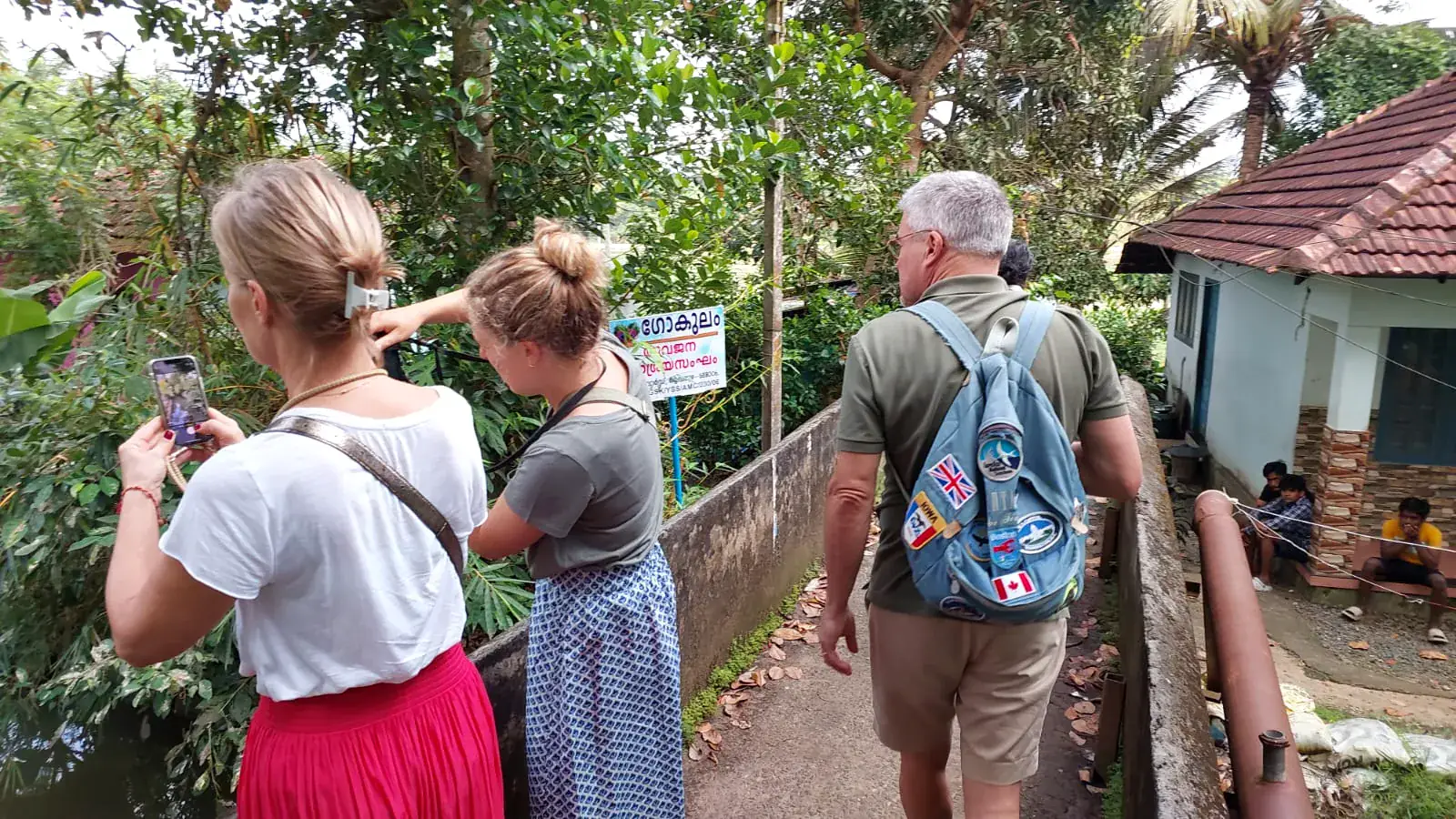 Guests walking along a waterside village path in Alleppey